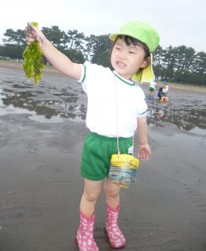 大きな海藻をもって自慢げな女の子